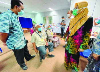 KAMARULZAMAN Ab. Wahab (kiri) meninjau keadaan warga emas yang menerima suntikan di Pasir Puteh, Kelantan. - UTUSAN/TOREK SULONG
