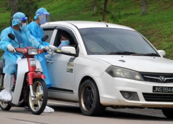 DUA petugas kesihatan mengedarkan borang maklumat kepada pemandu kenderaan yang akan membuat ujian calitan Covid-19 secara pandu lalu di Pusat Sehenti Penilaian Covid-19 (OSCAC) di Stadium Tertutup Majlis Bandaraya Pasir Gudang di Johor. - UTUSAN/RAJA JAAFAR ALI