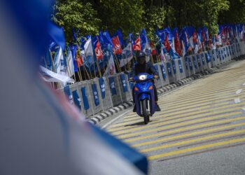 SEORANG penunggang motosikal melepasi deretan bendera parti politik yang bertanding pada Pilihan Raya Umum ke-15 (PRU15) di Jalan Tanah Lapang, Sentul, Kuala Lumpur. Tanggungjawab kini terletak di tangan kira-kira 21 juta pengundi untuk memilih pemimpin dan kerajaan yang akan menerajui Malaysia bagi tempoh lima tahun akan datang. – MINGGUAN/FARIZ RUSADIO