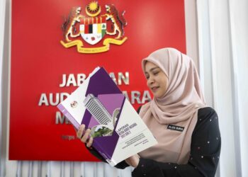 Penolong Pengarah Audit, Eliza Suria Mohd Noor melihat buku Laporan Ketua Audit Negara 2021 Siri 2 
di Kompleks F, Putrajaya, baru-baru ini. – mingguan/FAISOL MUSTAFA