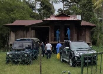 ANGGOTA polis dan pasukan paramedik lengkap berpakaian peralatan perlindungan diri (PPE) mengangkat mayat mangsa yang ditemui mati di rumahnya di Kampung Chuai Ulu, Rembau pagi tadi.-UTUSAN/NOR AINNA HAMZAH