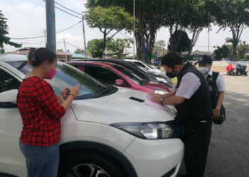 INSPEKTOR kesihatan mengeluarkan kompaun terhadap wanita yang masih menjalani kuarantin selepas hadir ke pusat mengundi di Dewan Kampung Melayu, Johor Bahru.