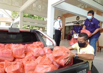 Sunarko (kiri) melihat petugas menyediakan bakul makanan untuk diagihkan kepada warga Indonesia yang terkesan akibat pandemik Covid-19 di Johor.