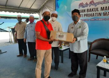 AHMAD Tarmizi (kanan) menyampaikan sumbangan kepada peserta MADA pada Majlis Penyerahan Bantuan Bakul Makanan Kementerian Pertanian dan Industri Makanan Prihatin MADA di Permatang Buloh, Yan, Kedah, hari ini. 