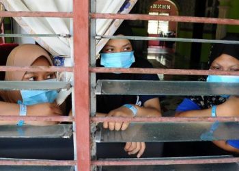 DARI kiri: Amira Shafiqqah Amir, Siti Meriam Yusuf dan Siti Nursyahadah Nasir yang memakai gelang biru termenung di dalam rumahnya akibat tidak dibenarkan keluar dalam tempoh kuaratin rumah selama dua minggu di Kampung Sedili Kecil, Kota Tinggi, Johor hari ini. - FOTO/RAJA JAAFAR ALI