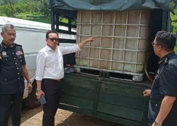 KAMALUDDIN Ismail (tengah) menunjukkan tangki berisi cecair disyaki diesel bersubsidi dalam serbuan di sebuah kilang papan tidak bernombor di Kampung Chuar Hulu dekat Sauk, Kuala Kangsar hari ini. - UTUSAN