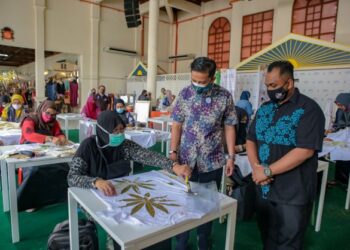 KHAIRUL Hafizi Naharuddin (tengah) melihat peserta Makmal Kraf Eco Print menghasilkan kesan corak dari tumbuhan pada baju di  PASAREKA 2021 di Kompleks Kraf Langkawi, semalam.
