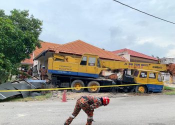ANGGOTA bomba memeriksa keadaan sebuah kren yang merempuh lima kenderaan dan tiga rumah selepas mengalami kerosakan enjin di Taman Puncak Bukit Jalil, Melaka, semalam.