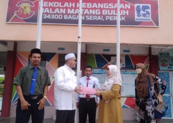 RAZMAN Zakaria (dua dari kiri) menyampaikan kek kepada guru sempena sambutan Hari Guru di SK Matang Buluh di Bagan Serai hari ini. - UTUSAN/WAT KAMAL ABAS