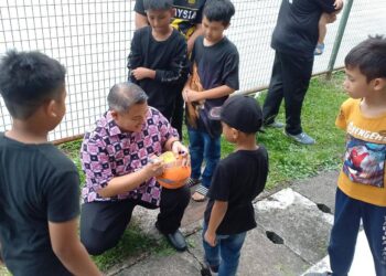 RAIS Yasin menurunkan tanda tangan pada sebiji bola futsal selepas merasmikan Hari Keluarga PPR Krubong 2023. - UTUSAN/AMRAN MULUP