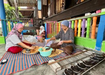 Maznah Ahmad (kanan) bersama Rohani Othman (tengah) dan Mariani Mat Dahan menyiapkan tempahan kuih sepit di Kampung Seberang Ramai, Kuala Perlis, semalam. – UTUSAN/ASYRAF MUHAMMAD