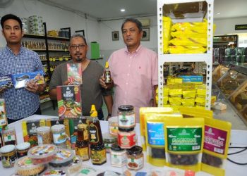 Amir Pasha (dari kiri) bersama bapanya, Mustapha Pasha (kanan) dan Pengarah ERA SAG Sdn. Bhd., Syed Zain Alwee menunjukkan sebahagian produk makanan sunah yang terdapat 
di Saudagar Kurma. – utusan/RAJA JAAFAR ALI