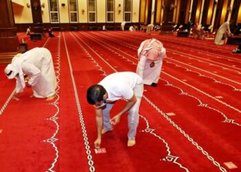 JEMAAH masjid menanggalkan pelekat penjarakan fizikal di masjid Kuwait City, 21 Oktober, tahun lalu.-AFP