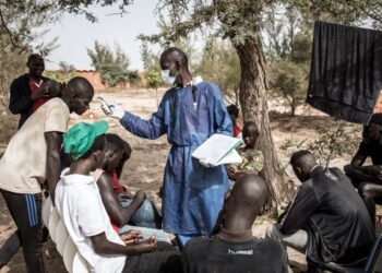 PETUGAS perubatan memeriksa suhu badan penduduk di pusat kuarantin untuk golongan pelarian di Dakar, Senegal. - AFP