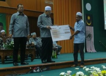 AHMAD Yakob (dua kiri) menyampaikan cek kepada wakil pada Majlis Himpunan Perdana Peserta Ladang Rakyat Negeri Kelantan dan Pembahagian Dividen Ladang Rakyat Peringkat Ke-56 di Kota Bharu, Kelantan hari ini. UTUSAN/MUSTAQIM MOHAMED