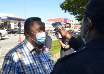 MOHD. Zaidi Aziz menjalani pemeriksaan suhu sebelum meninjau proses pengundian awal di IPD Muallim, Tanjung Malim hari ini. - FOTO/ZULFACHRI ZULKIFLI