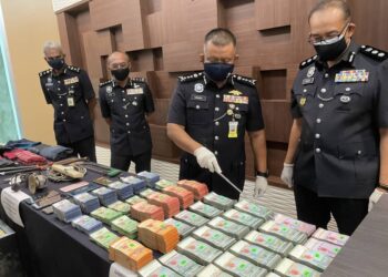 KAMARUL Zaman Mamat menunjukkan sebahagian wang tunai yang dirampas daripada enam lelaki termasuk tiga anggota polis yang ditahan di Alor Setar, hari ini. - UTUSAN/JAMLIAH ABDULLAH