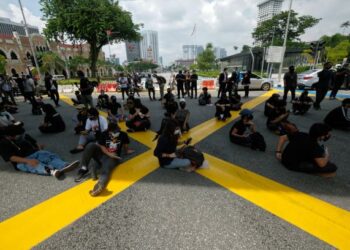 KUMPULAN peserta berpakaian hitam duduk di atas jalan raya sambil diperhatikan o polis ketika protes #LAWAN di persimpangan Jalan Tun Perak dan Jalan Raja, Kuala Lumpur, hari ini. -UTUSAN/ MUHAMAD IQBAL ROSLI