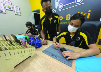 MUHAMMAD Ameer Hakim Azani (tengah) bersama rakan-rakan menawarkan perkhidmatan membaiki peranti dan telefon pintar dengan membuka I Go Baiki di Pasir Puteh, Kelantan. – UTUSAN/TOREK SULONG