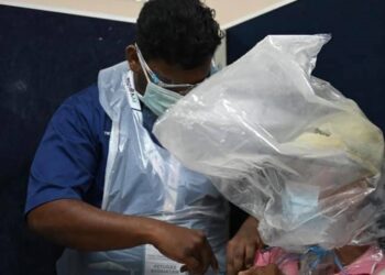 LELAKI warga emas yang berbungkus kepala dengan plastik ketika mendapatkan suntikan vaksin Covid-19 di Pusat Pengambilan Vaksin, Universiti Sains Malaysia (USM) semalam. - FOTO FB USM