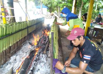 ZAINORA Aziz (dua dari kanan) membakar lemang sambil dibantu pekerjanya di gerai Lemang Cik Nora di Kampung Durian Daun, Masjid Tanah, Melaka. - UTUSAN/MUHAMMAD SHAHIZAM TAZALI
