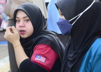 SAIDATUL ALIA Ahmad, 26, (kiri)  tidak dapat menahan sebak selepas mendapat berita tentang kehilangan adiknya, Muhamad Ikhmal Hakim, 20, di Pantai Teluk Chempedak di Kuantan, Pahang. - FOTO/SHAIKH AHMAD RAZIF