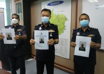 MOHD. Fadhil Minhat (tengah) menunjukkan wajah suspek yang dikenali sebagai Long Tiger yang kini diburu polis di IPD Tangkak, Johor. -UTUSAN/NUR ALINA HASSAN