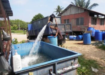 ISMAIL Hashim (kanan) memerhatikan seorang pekerja kontraktor SADA mengisi air ke dalam tong yang disediakan di hadapan rumahnya di Kampung Segantang Garam, Merbok, Sungai Petani, Kedah, semalam. – FOTO/OTHMAN YAHAYA