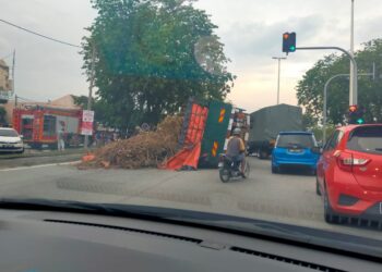 Lori yang membawa muatan dahan kayu terbalik di Jalan Kuala Kangsar, Tasek, Ipoh, kelmarin.