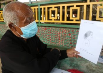 HUSAIN Jaafar menunjukkan lukisan satira dihasilkannya bagi menzahirkan kritikan di Pekan Lama Chenor,  Maran, Pahang, semalam. –  UTUSAN/SALEHUDIN MAT RASAD