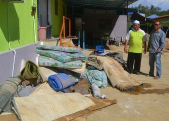 MOHD. Khairul Poniran (kiri) melihat peralatan asrama seperti tilam, karpet dan tikar yang rosak akibat banjir kilat di Madrasah Darul Uloom Al-Islamiyah Jengka, Maran, Pahang.