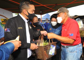 ONN Hafiz Ghazi (kiri) mengadakan jualan promosi bakul lodeh berharga RM10 bersama Ahmad Hamzah (dua kiri) kepada pengunjung Program Jualan Semarak Syawal 2022 Peringkat Negeri Johor di Pasar Tani Datin Halimah, Johor Bahru di sini. UTUSAN/RAJA JAAFAR ALI