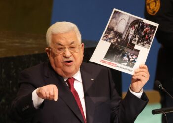 MAHMUD ABBAS memegang gambar mengenai kekejaman tentera Israel semasa UNGA di New York.-AFP