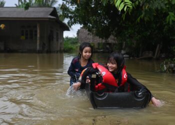 DUA beradik, Nur Irina Maria Ruzali dan Nur Aisha Alia Ruzal bermain air banjir di pekarangan rumah mereka di Kampung Nyatuh, Setiu, Terengganu. - UTUSAN/PUQTRA HAIRRY ROSLI