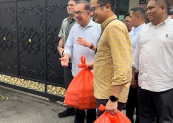 ANWAR dan pembantunya mengedarkan makanan  tengah hari kepada petugas media yang berkumpul dI pekarangan pejabatnya.