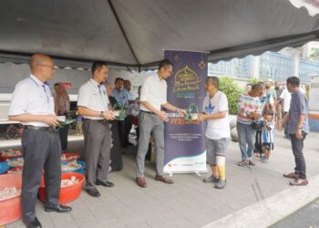 ANWAR Syahrin Abdul Ajib (tiga dari kiri) mengedarkan bubur lambuk kepada orang ramai pada Program Kongsi Berkat Bubur Lambuk Media Mulia Sdn. Bhd. bersama Malakoff di Masjid Jamek Kampung Baru, Kuala Lumpur. – UTUSAN/SHIDDIEQIIN ZON