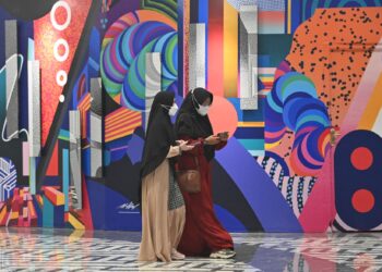 DUA wanita memakai pelitup muka ketika mengunjungi pusat beli-belah di Jakarta.-AFP