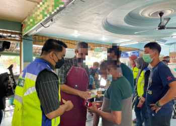 PENGUAT KUASA JAIM memeriksa dokumen pengenalan diri pekerja restoran yang bertindak sebagai ulat dalam serbuan di sebuah restoran mamak di Peringgit, Melaka. - UTUSAN/DIYANATUL ATIQAH ZAKARYA