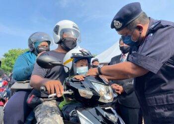 ZAINOL Samah (kanan) memakaikan topi keledar berkualiti kepada seorang kanak-kanak ketika melancarkan Op Selamat Ke-18 peringkat negeri di Ayer Keroh, Melaka. - UTUSAN/DIYANATUL ATIQAH ZAKARYA