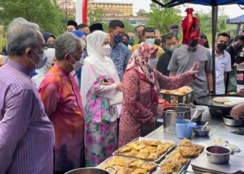 TUNKU AZIZAH Aminah Maimunah Iskandariah (kiri, depan) bertitah mengenai resipi martabak kepada Mohd. Razi Hamid ketika kunjungan Seri Paduka ke Bazar Ramadan Peringgit, Melaka. - UTUSAN/DIYANATUL ATIQAH ZAKARYA