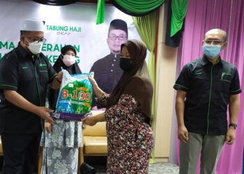 AHMAD Marzuk Shaary (kiri) menyampaikan sumbangan pek makanan kering kepada salah seorang penerima di Bangunan Tabung Haji Kelantan, di Kota Bharu, Kelantan hari ini. - UTUSAN/YATIMIN ABDULLAH
