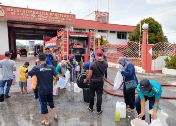 PENDUDUK mengambil bekalan air bersih yang disalurkan oleh pasukan bomba di pekarangan premis pasukan itu di Seri Manjung semalam. - UTUSAN/JPBM PERAK