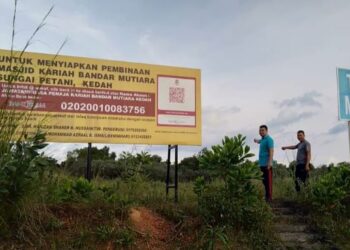 ZAHIR Said (kiri) ditemani seorang penduduk menunjukkan 
papan tanda tapak pembinaan masjid baru di Bandar Mutiara, 
Sungai Petani. – UTUSAN/OTHMAN YAHAYA