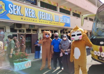 PENERIMA vaksin di PPV Bergerak Peringkat Daerah Jempol di SK (Felda) Lui Selatan, Jempol tidak melepaskan peluang untuk mengambil gambar bersama dua maskot yang hadir bagi menceriakan suasana di PPV berkenaan. - UTUSAN/NOR AINNA HAMZAH
