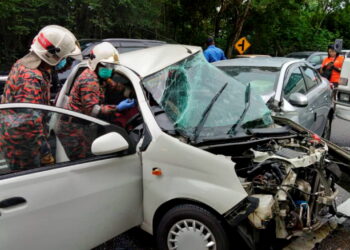 ANGGOTA bomba  mengeluarkan mangsa kemalangan di Jalan Ipoh-Lumut, di Ipoh hari ini. - GAMBAR JBPM