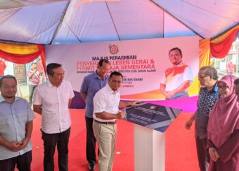 AMIRUDIN Shari (tengan) menandatangani plak penyerahan gerai majlis pada program Perasmian Penyerahan Lesen dan Permit Penjaja Sementara Bandar Baru Sungai Buloh, Selangor. UTUSAN/MOHAMAD HAFIZI MOHD SAID.