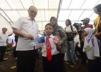 WAN ROSDY Wan Ismail (kiri) menyampaikan Bantuan Prihatin Pahang (BPP) kepada murid darjah satu di Sekolah Kebangsaan (SK) Mat Kilau di Kuantan, Pahang. - FOTO/SHAIKH AHMAD RAZIF