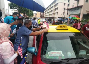 MOHD. Noorazam Osman (kanan) melekatkan bendera Jalur Gemilang dan menyerahkan bakul makanan kepada pemandu teksi di PPR Stulang, di Johor Bahru, Johor.