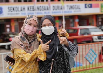 Izzate Khasbullah, 31, (kiri) bersama adiknya Izyan Ainaa Khasbullah, 23, menunjukkan dakwat di jari selepas menunaikan tanggungjawab pada hari mengundi Pilihan Raya Negeri (PRN) Melaka di Sekolah Kebangsaan Durian Tunggal, Alor Gajah. -UTUSAN/RASUL AZLI SAMAD