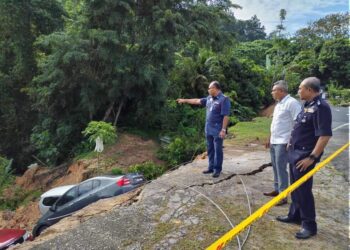 MOHD. Nizam Tajul Arus bersama Mohammad Idris (kiri) dan Nanda Maarof melihat kawasan runtuhan tanah dan mendap yang berlaku di Taman Bukit Berlian, Seremban hari ini.